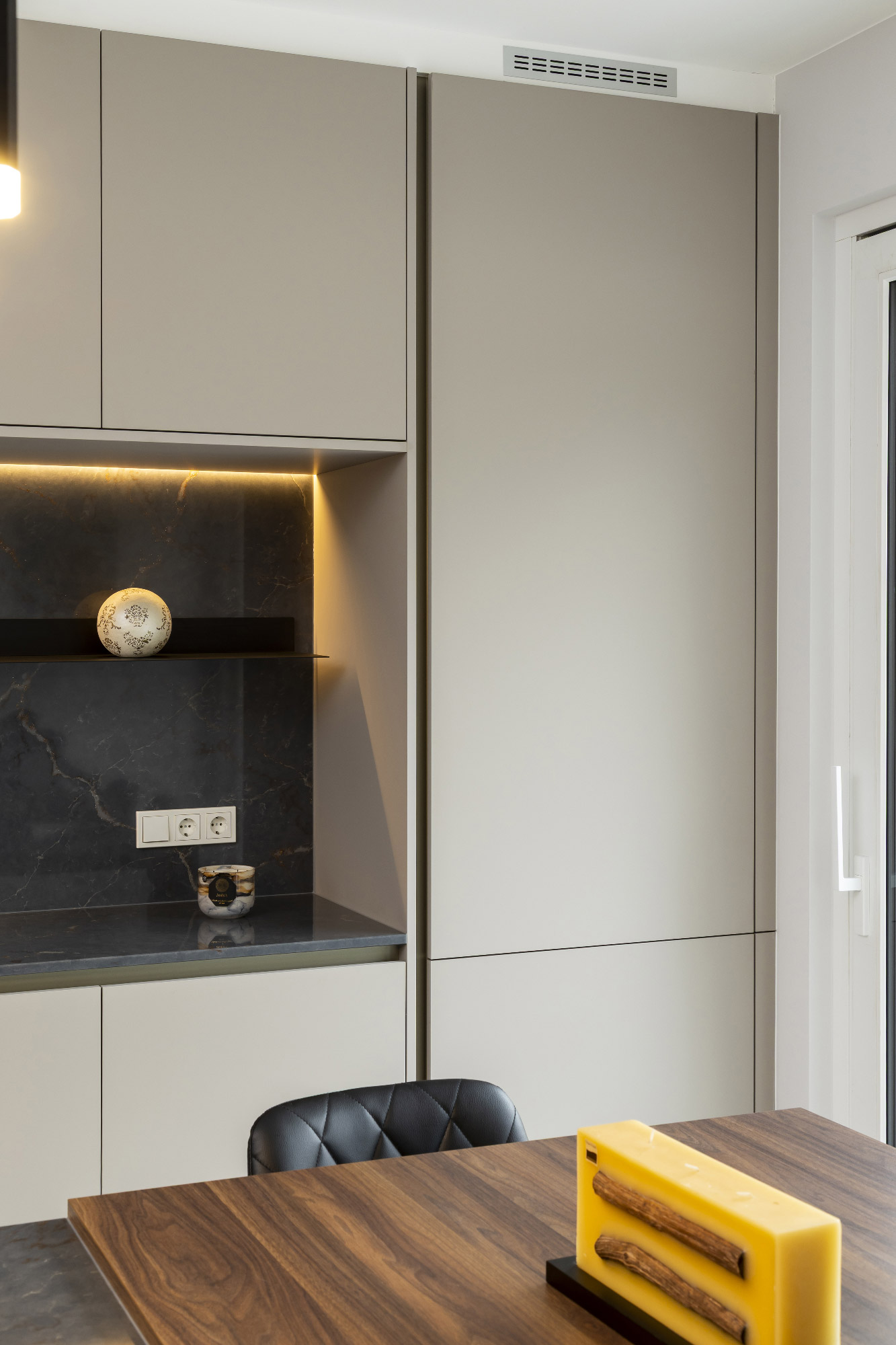 Parete cucina con armadi a tutta altezza in finitura Sandalo, retro in marmo scuro e mensola decorativa illuminata a LED