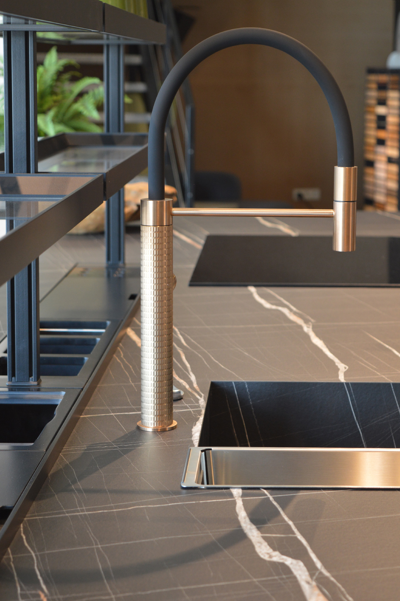 Rubinetto moderno in ottone satinato con collo nero opaco su piano cucina effetto marmo nero con venature bianche, design di lusso contemporaneo.