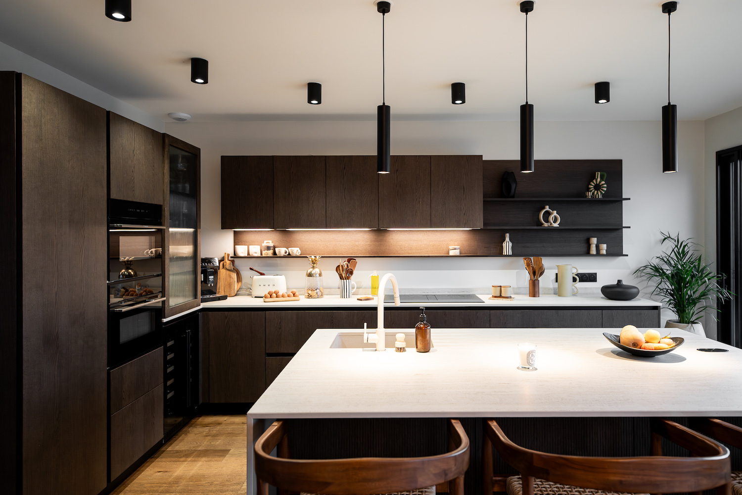 Cucina Zecchinon con isola centrale, caratterizzata da volumi in legno scuro che si alternano a superfici chiare e luminose.