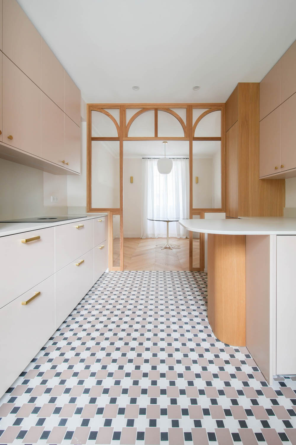 Cucina Zecchinon rosa cipria con inserti e colonne in legno, piano cottura bianco. Struttura in legno che separa la cucina dalla zona soggiorno.