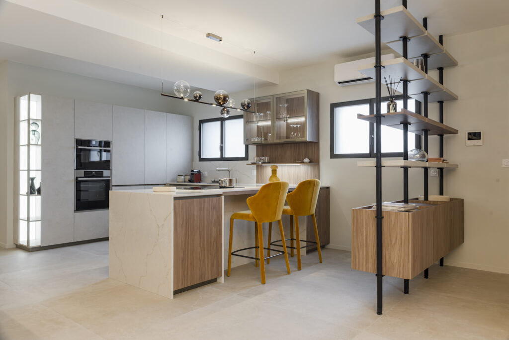 Cucina Zecchinon con penisola e materiale tecnico chiaro con venature, lampadario moderno, sgabelli gialli e libreria Zecchinon